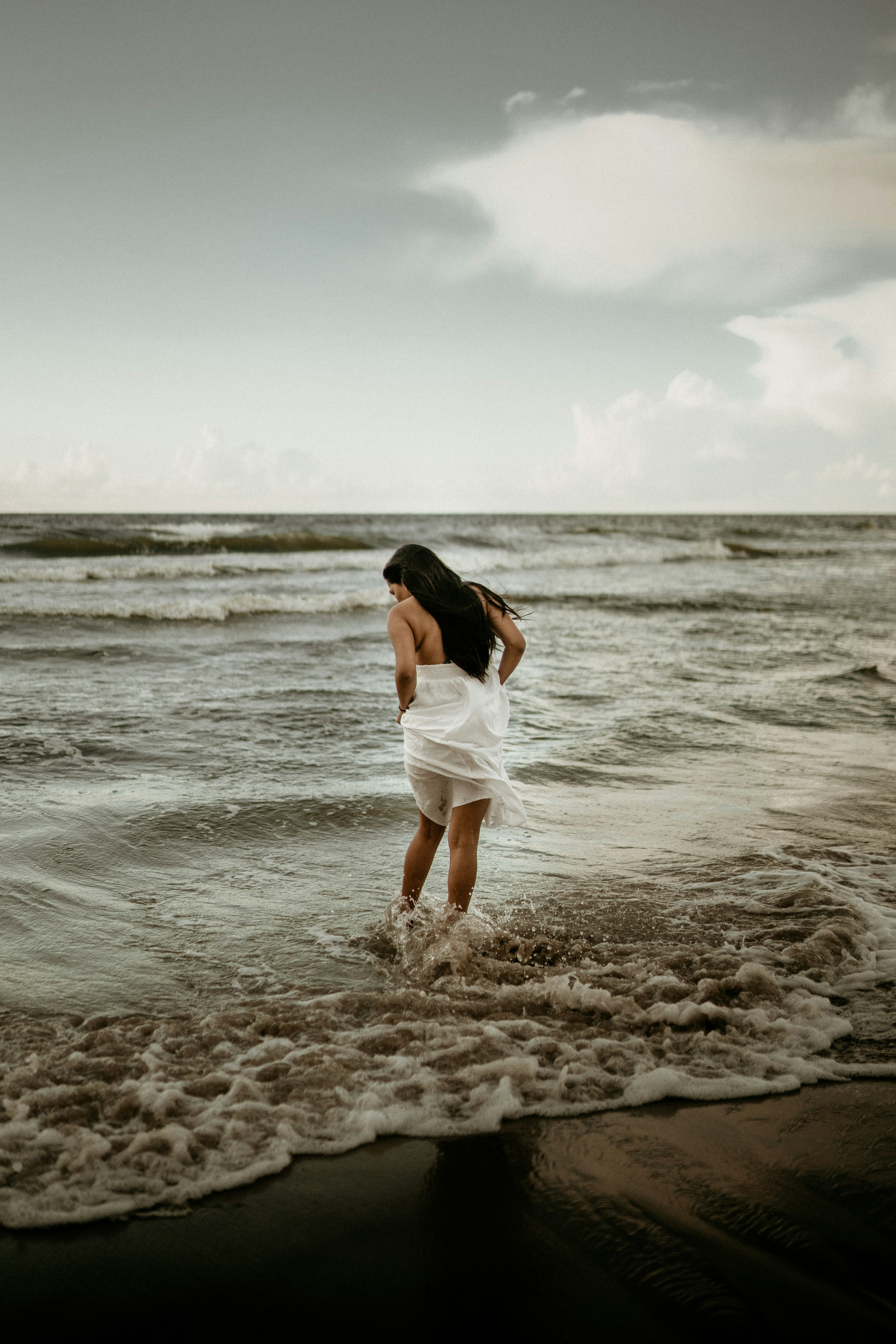 woman in white dress standing on beach during daytime